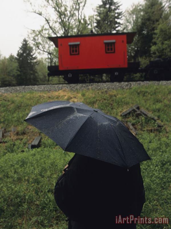 Person Under an Umbrella Looking at a Parked Train Caboose painting - Raymond Gehman Person Under an Umbrella Looking at a Parked Train Caboose Art Print