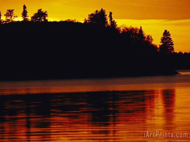 The Setting Sun Casts an Orange Glow Over Manitoba's White Lake painting - Raymond Gehman The Setting Sun Casts an Orange Glow Over Manitoba's White Lake Art Print