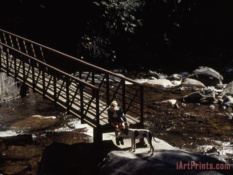Woman And Dog Resting at a Footbridge Across The Whitewater River painting - Raymond Gehman Woman And Dog Resting at a Footbridge Across The Whitewater River Art Print