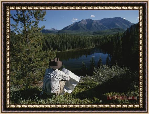 Raymond Gehman A Man with a Cowboy Hat Reads a Map And Gazes Across a River Framed Print