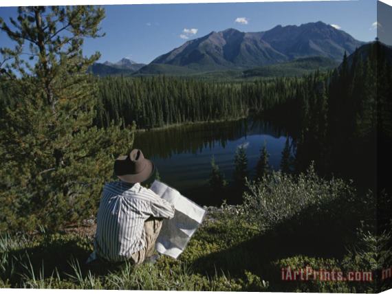 Raymond Gehman A Man with a Cowboy Hat Reads a Map And Gazes Across a River Stretched Canvas Painting / Canvas Art