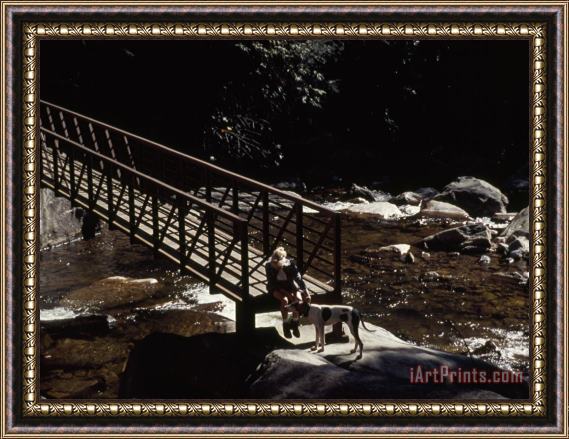 Raymond Gehman Woman And Dog Resting at a Footbridge Across The Whitewater River Framed Print