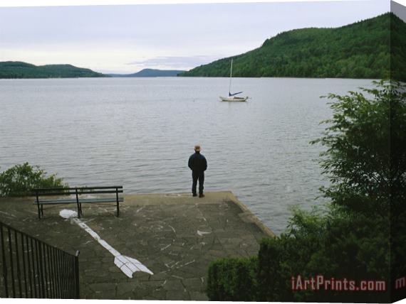Raymond Gehman A Man Looks Out at a Sailboat Anchored on Otsego Lake Stretched Canvas Print / Canvas Art