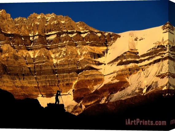 Raymond Gehman A Photographer Is Silhouetted Against a Dramatic Mountain Backdrop Stretched Canvas Painting / Canvas Art