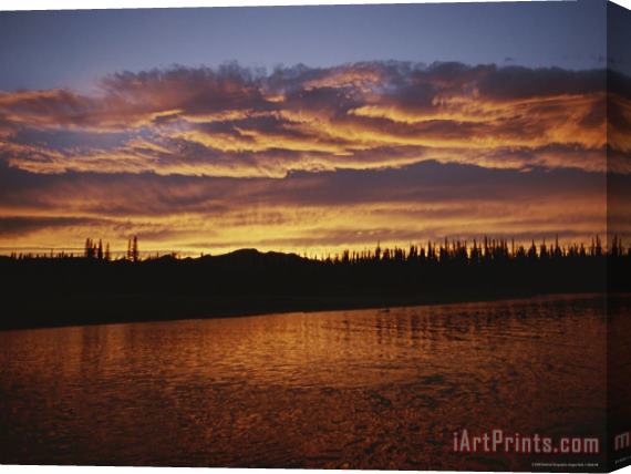 Raymond Gehman An Intense Sunset Colors Clouds And The Water of The Mackenzie River Stretched Canvas Print / Canvas Art