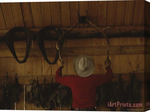 Raymond Gehman An Outfitter Hangs a Set of Elk Antlers on a Cabin Wall Stretched Canvas Print / Canvas Art