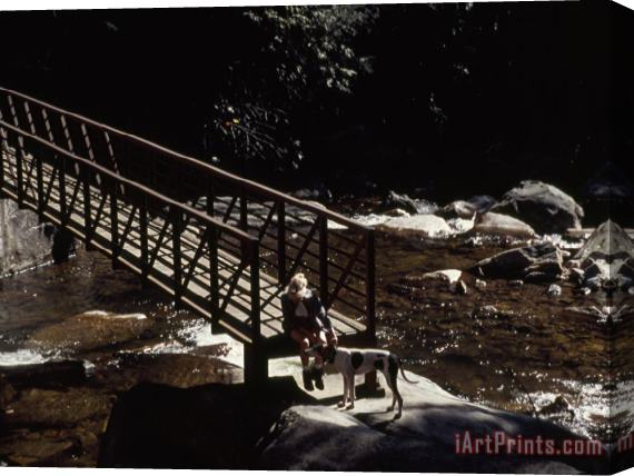 Raymond Gehman Woman And Dog Resting at a Footbridge Across The Whitewater River Stretched Canvas Print / Canvas Art